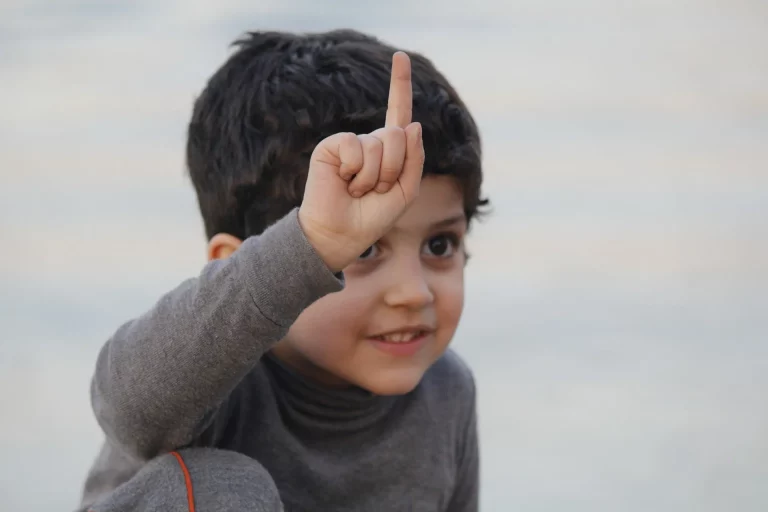 young boy doing number one hand sign