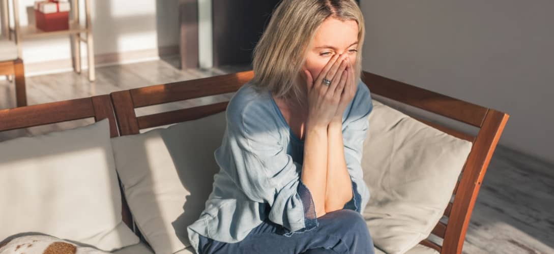 Frustrated nervous sad middle aged woman sitting on sofa